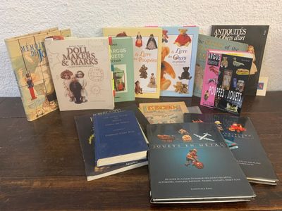 plusieurs livres pour enfants posés sur une table en bois, avec un mur blanc en arrière-plan