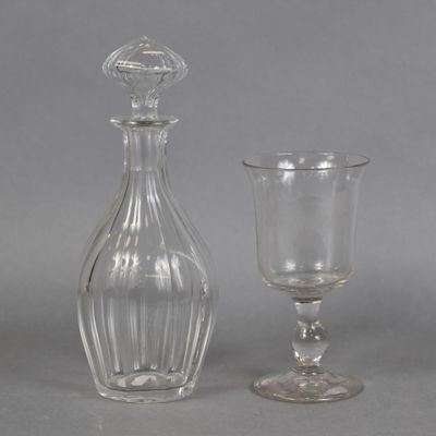 a glass bottle and a glass goblet sitting next to each other