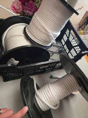 une personne tenant une bobine de corde à côté d'un panier rempli de bobines