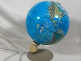 un globe bleu posé sur un socle, sur fond blanc