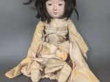 une vieille poupée aux longs cheveux noirs, assise par terre