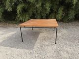 une petite table en bois aux pieds noirs, posée sur un sol recouvert de gravier