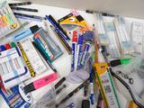 many different pens and pencils on the table