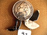 a small silver coin with a small blade attached to it