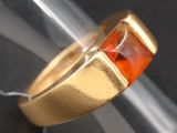 an image of a close up of a ring with an orange stone in it