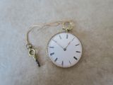 une petite horloge à laquelle est accrochée une clé sur le côté