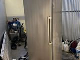 a silver refrigerator in the middle of a room with a lot of trash