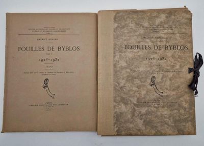 un vieux livre orné d'un ruban noir est ouvert sur une surface blanche