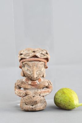 une figurine posée à côté d'une poire sur une table