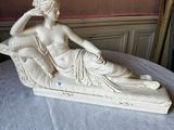 a statue of a woman sitting on top of a bed
