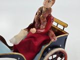 a figurine of a woman sitting in a horse drawn carriage
