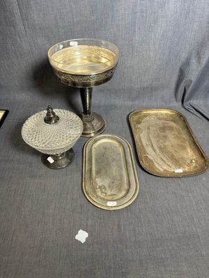trois plateaux en argent et une assiette en argent posés sur une nappe grise