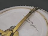 a gold clock on a white plate on a table