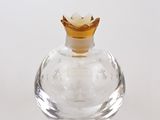 une petite bouteille en verre transparent avec un bouchon doré