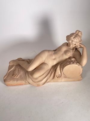 statue d'une femme allongée sur un oreiller, posée sur une surface blanche