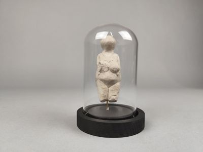 une photo d'une figurine représentant une femme sous une cloche en verre