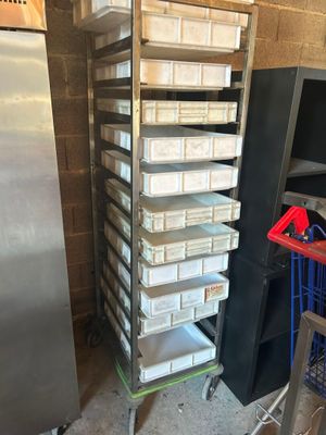 Plusieurs plateaux de nourriture sont empilés sur un chariot dans une cuisine