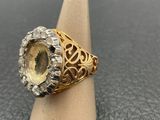 a gold and silver ring with an oval cut citrine stone surrounded by diamonds