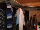 a closet full of clothes and sweaters hanging on a rail