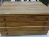 a wooden chest of drawers on a table in a room