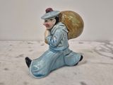 une petite figurine représentant une femme portant un sac