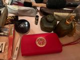 a red purse sitting on a table with makeup and other items