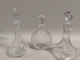 trois flacons de parfum en verre transparent posés sur une table blanche