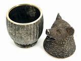a cat statue next to a cup on a white surface
