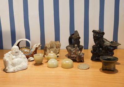 Plusieurs figurines sont posées sur une table en bois, devant un papier peint à rayures bleues et blanches.