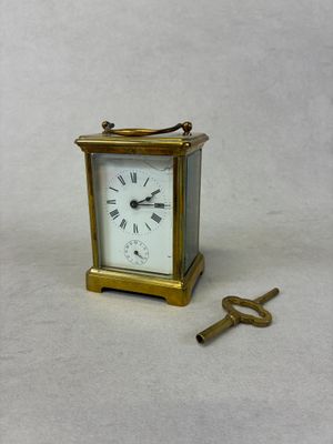 une petite horloge et une clé posées sur une table