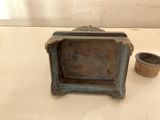 a small metal box sitting on a table next to a cup