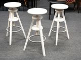 trois tabourets blancs posés sur un sol recouvert de moquette, à côté d'une table