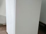 a small white refrigerator sitting on the floor in a room