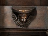 a wooden cabinet with a carving of a man ' s head on it