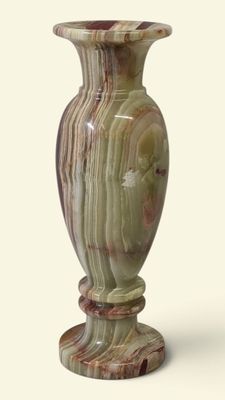 a vase that is sitting on a stand on a white surface