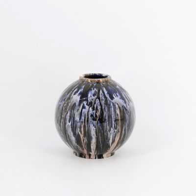 un vase noir et blanc posé sur une surface blanche