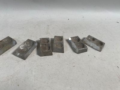 six pièces métalliques sont disposées en ligne sur une surface blanche