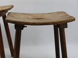 pair of wooden stools with bent legs on a white background