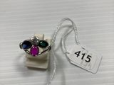un gros plan d'une bague en argent sertie de pierres violettes et vertes