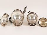 an assortment of silverware including a teapot, cups and saucer