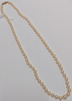 a close up of a pearl necklace on a white surface
