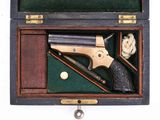 une boîte en bois contenant un pistolet et une balle
