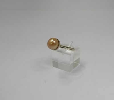 a close up of a gold pearl on a clear stand