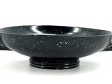 a black bowl that is sitting on a white surface