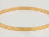 gros plan d'un bracelet en or sur une surface blanche