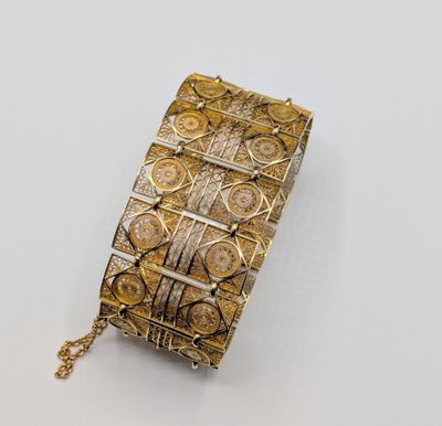 a close up of a gold and silver bracelet on a white surface