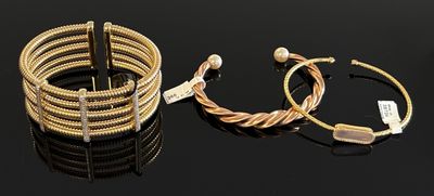 two gold bracelets and a bracelet with pearls on a black surface
