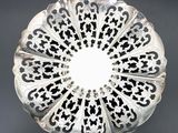 silver plate with black and white designs on it on a black surface