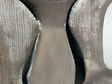 a silver vase with a black handle sitting on a table