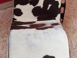 a brown and white cow print chair on a tile floor